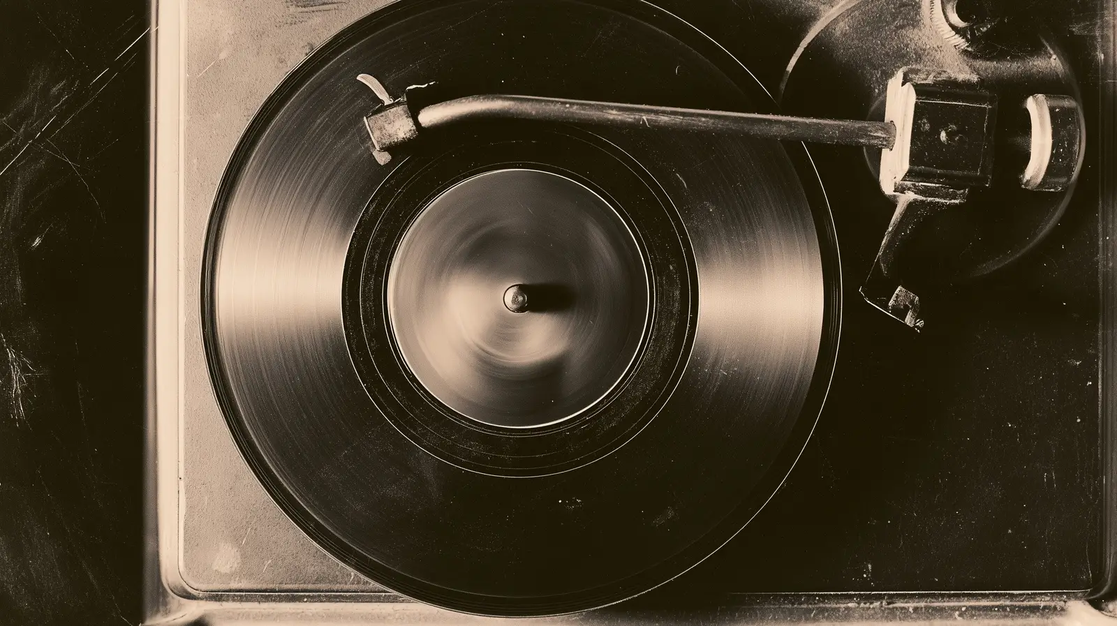 A record turning on a worn turntable seen from directly above, the tonearm resting across it and the label blurred by the rotation.